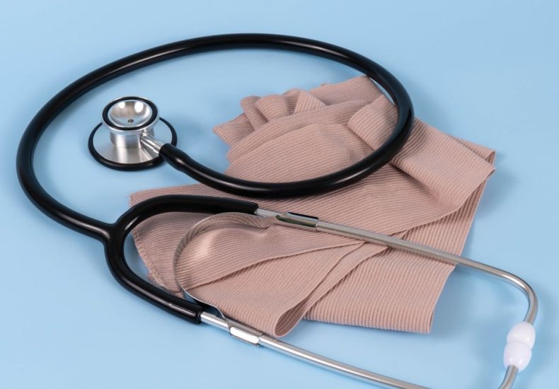Stethoscope and bandage on a pastel blue background.